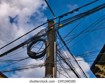Chaotic electrical supply cabling on a pole on a street in Kampot, Cambodia
