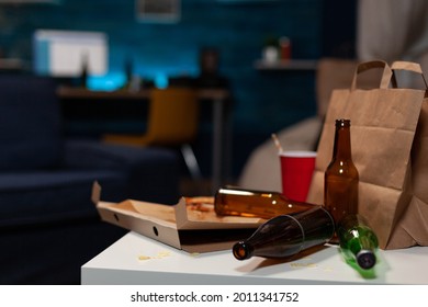 Chaotic Home Of Lonely Person With Sever Mental Health Problem Having Rubbish On Messy Table With With Beer Bottles And Food Leftover. Empty Living Room Of Depressed Untidy Person With Depression