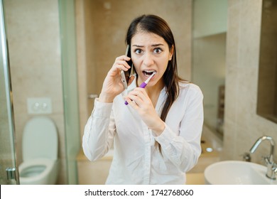 Chaotic preparation for work in the morning.Young woman talking on the phone while brushing teeth and putting on clothes.Busy businesswoman getting ready.Being late to work.Organizational multitasking