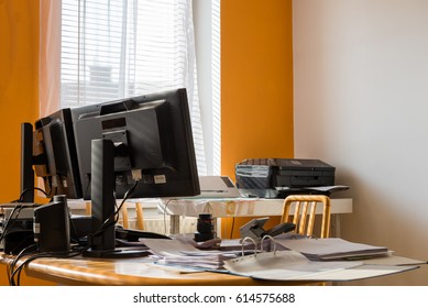 Chaotic Writing Desk With Two Monitors And A Printer In The Background - Folders, PC