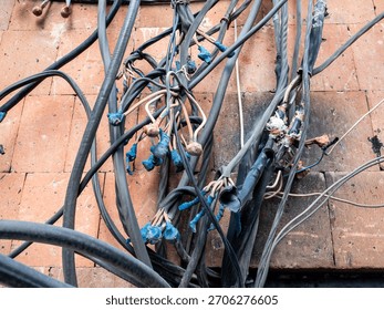 Chaotically tangled electrical cables of external wiring on wall of pink tuff stone house in Yerevan city, Armenia in autumn twilight