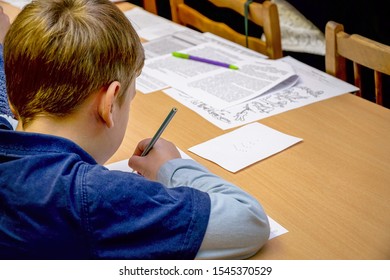 Chapaevsk, Samara region, Russia - October 15, 2019: Elementary school of the city of Chapaevsk. Schoolboy sitting at a desk writes on a sheet of paper. Back view. Soft focus. Selective focus