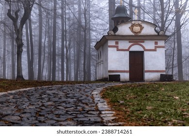 Chapel with stone path in forest with fog. Evening clouds around Chapel of the Holy Sepulcher, Czechia. - Shutterstock ID 2388714261