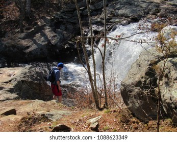 Chapman Falls waterfall located at Devil's Hopyard State Park with a man exploring the rocks and potholes 