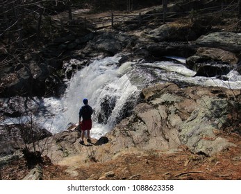 Chapman Falls waterfall located at Devil's Hopyard State Park with a man exploring the rocks and potholes 