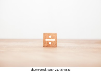 The character of ÷. divide. division. division. Written on a wooden block. White letters. Wooden table background. - Shutterstock ID 2179646533