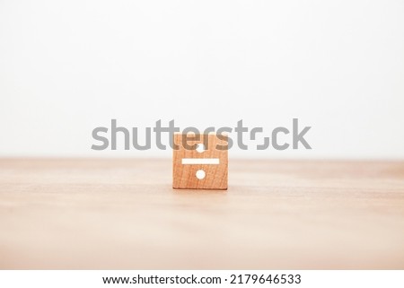 The character of ÷. divide. division. division. Written on a wooden block. White letters. Wooden table background. Foto d'archivio © 