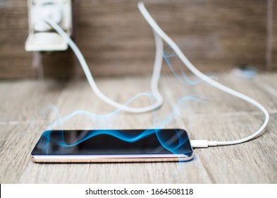 Charching Android Phone Battery Connected To Electricity Wire.Overheating Mobile Phone  Plugged In To Charge All Night.Smoke From Black Screen Of Cell Phone. Overcharging Concept