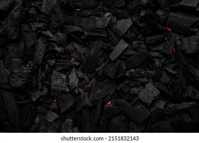 Charcoal with red streaks of heat. Textured dark background.