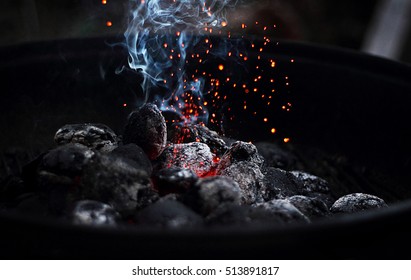Charcoal that is smoking and burning on a grill