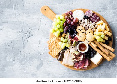 Charcuterie board. Cheese platter: Parmesan, maasdam, camembert, cheddar, gouda with prosciutto, salami, fruits and nuts. Assortment of tasty appetizers or antipasti. Top view. Copy space. - Powered by Shutterstock