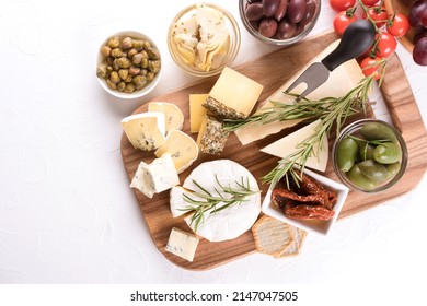 Charcuterie board with cheese slices and assortment of traditional Italian antipasti. Cheese platter on white table with copy space