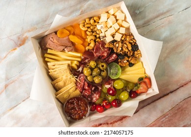 charcuterie box with cheeses, crackers, strawberries, olives, grapes, cherries, pastrami, salami, apricot and walnuts - Powered by Shutterstock