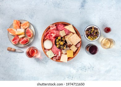Charcuterie and cheese board, overhead flat lay shot with copy space. Italian antipasti, shot from above with wine, olives, and sanwiches. Mediterranean delicatessen