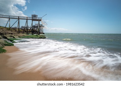 Charente Maritime, France near seaside resort Royan with waves breaking on sandy beach and fishing huts on stilts on rocky coastline - Powered by Shutterstock