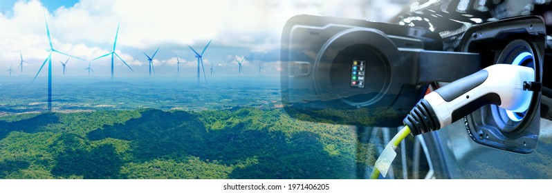 Charge EV car vehicle electric battery power with blur wind turbine blue sky on panoramic background. The idea for nature electric energy technology green eco car environment friendly concept.