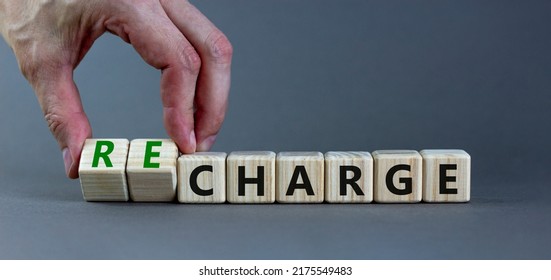 Charge Or Recharge Symbol. Businessman Turns Wooden Cubes And Changes The Word 'charge' To 'recharge'. Beautiful Grey Table, Grey Background. Business Charge Or Recharge Concept. Copy Space.