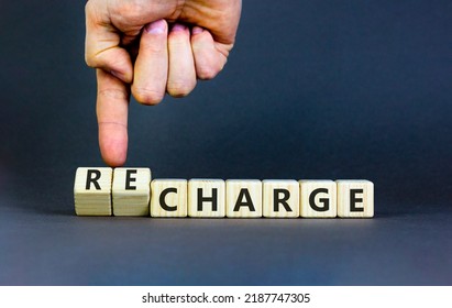 Charge Or Recharge Symbol. Businessman Turns Wooden Cubes And Changes The Word 'charge' To 'recharge'. Beautiful Grey Table, Grey Background. Business Charge Or Recharge Concept. Copy Space.