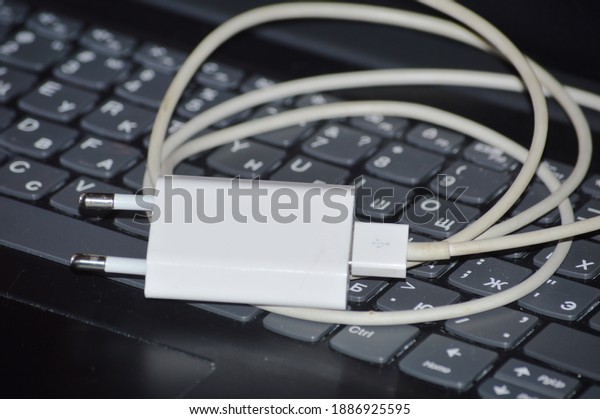 Charger for smartphone on the background of\
laptop keyboard