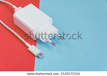 Charger and USB cable type C over pink and blue background
