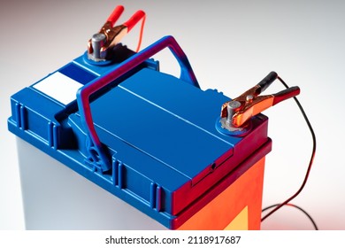 Charging the car acid battery. The charger terminals are connected to the battery. Car acid battery with charger terminals close-up. The automobile battery is charged with electricity. Car service.