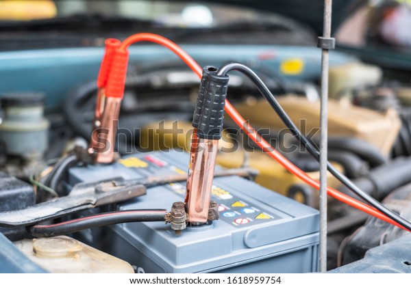Charging a car battery with electricity through\
cables from another\
car