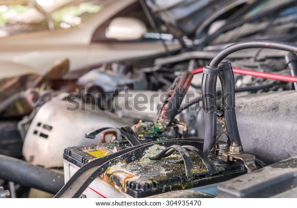 Charging car with electricity trough cables in auto\
repair shop.