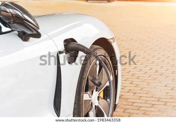 Charging\
an electric car at hybrid engine gasoline and electricity.\
Refueling for cars e-mobility. Close up\
supply