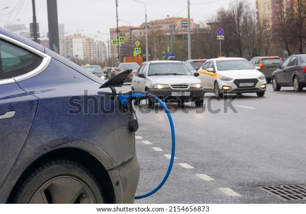 Charging an electric car on\
the background of cars moving along the street.                    \
         