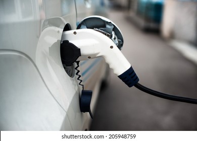 Charging an electric car with the power cable supply plugged in.