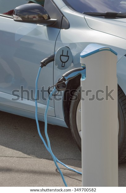 Charging an electric car with the power cable\
supply plugged in,\
closeup
