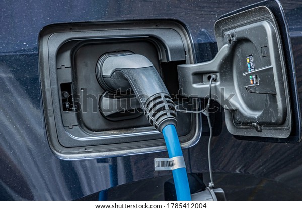 Charging an electric car with the power\
cord plugged into a charging station in the city of Maastricht, the\
Netherlands. Environmental awareness and green\
energy