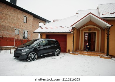 Charging Electric Car In The Yard Of House At Winter.