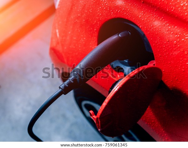 Charging an electric vehicle in the car\
service. Future of the automobile. Red\
colors