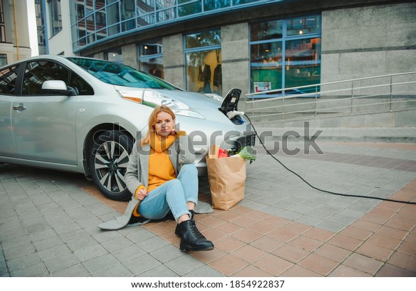 Charging electro car at the electric gas station.\
Woman by the car.