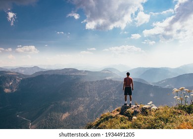 Charging energy in wild Austrian nature. Athlete of lighter figure with cap and red elastic trick stands on the edge of rock and enjoys feeling of relaxation and freedom. Conquering Mount Otscher. - Powered by Shutterstock