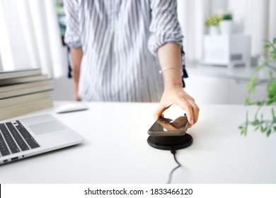 Charging Mobile Phone Battery With Wireless Charging Device In The Table. Smartphone Charging On A Charging Pad. Mobile Phone Near Wireless Charger