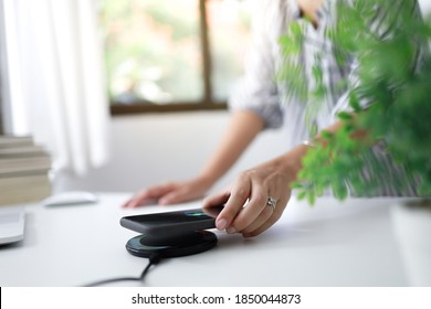 Charging Mobile Phone Battery With Wireless Charging Device In The Table. Smartphone Charging On A Charging Pad. Mobile Phone Near Wireless Charger