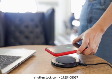 Charging Mobile Phone Battery With Wireless Charging Device In The Table. Smartphone Charging On A Charging Pad. Mobile Phone Near Wireless Charger