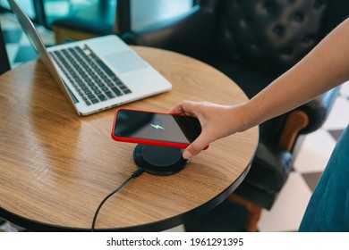 Charging mobile phone battery with wireless device in the table. Smartphone charging on a charging pad. Mobile phone near wireless charger