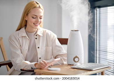 Charging mobile phone battery with wireless charging device on table, happy blonde female use modern technologies. Smartphone charging on charging pad. Mobile phone near wireless charger. Copy space - Powered by Shutterstock