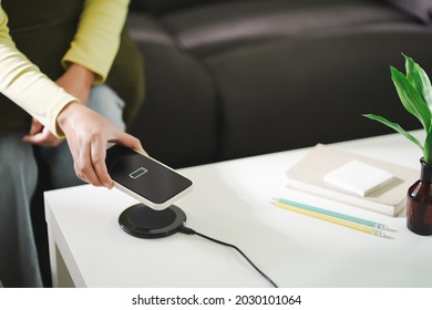 Charging Mobile Phone Battery With Wireless Charging Device In The Table. Smartphone Charging On A Charging Pad. Mobile Phone Near Wireless Charger.