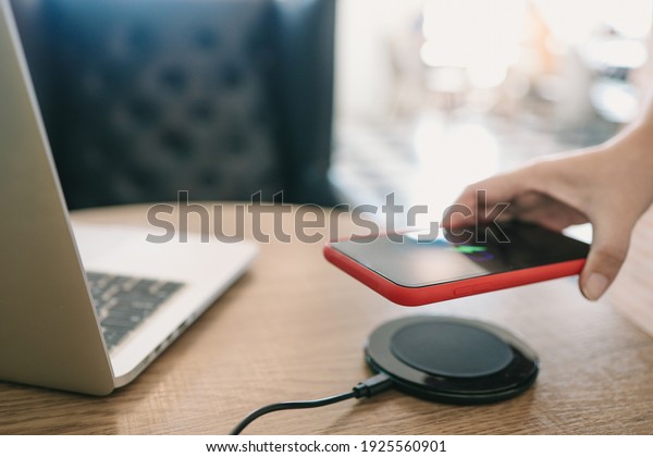 Charging mobile phone battery with wireless\
charging device in the table. Smartphone charging on a charging\
pad. Mobile phone near wireless\
charger