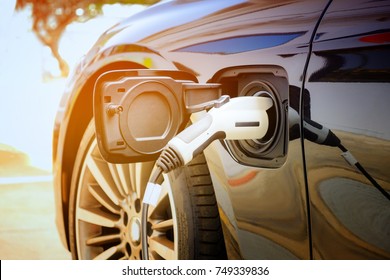 Charging modern electric car battery on the street which are the future of the Automobile, Close up of power supply plugged into an electric car being charged for hybrid . New era of vehicle fuel.