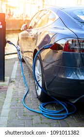 Charging modern electric car on the street in rays of the sun. Vehicle Rechargeable Batteries, future of transportation - Shutterstock ID 1091011382