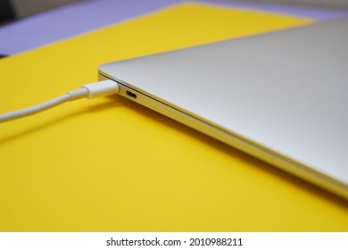 
charging a modern laptop with a USB-C charger. Laptop on a yellow background