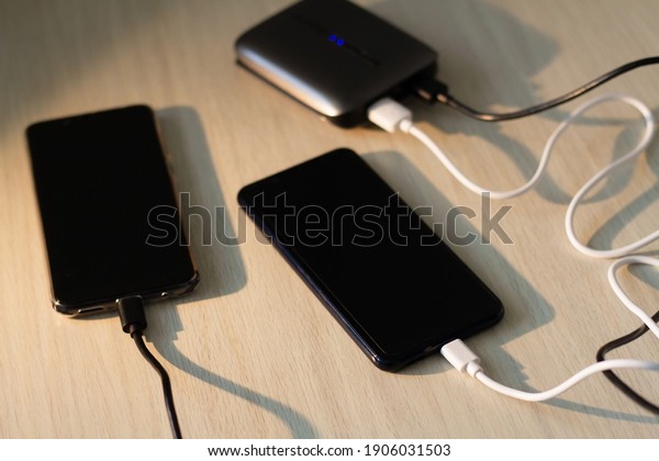 Charging your smartphone from a portable\
charger, close-up.