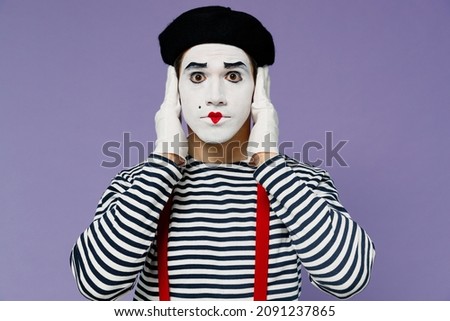 Charismatic amazing ecstatic young mime man with white face mask wears striped shirt beret cover ears with hands do not want to listen isolated on plain pastel light violet background studio portrait