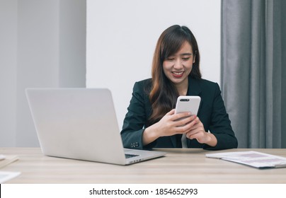 A Charismatic Business Man Uses A Cell Phone While Sitting Alone In A Modern Office During His Free Time To Relax After A Hard Day's Work.