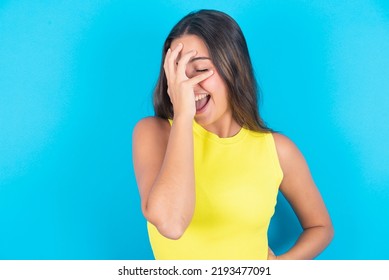 Charismatic Carefree Joyful Beautiful Brunette Woman Wearing Yellow Tank Top Over Blue Background Likes Laugh Out Loud Not Hiding Emotions Giggling Hear Funny Hilarious Joke Chuckling Facepalm.